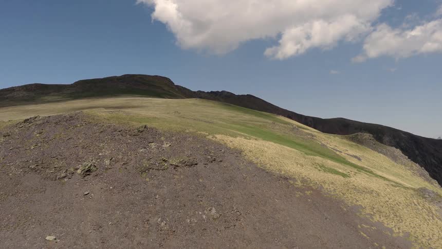Aerial fly over of a mountainous landscape on a sunny day