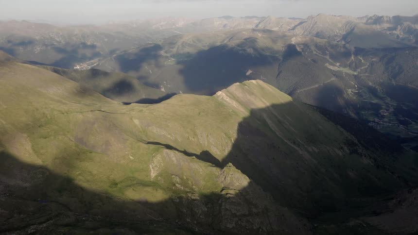 Sunlight shines on a mountain slope with mountains across the landscape