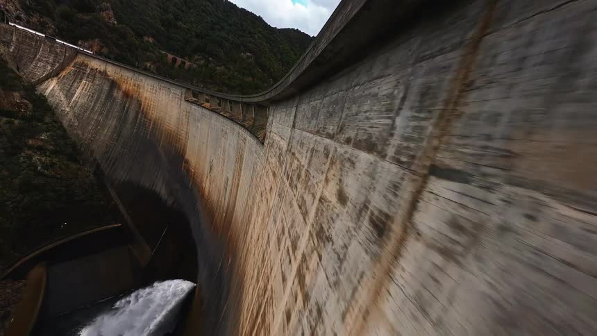 Water pours under the large dam
