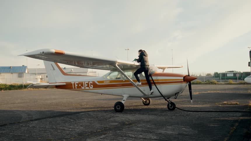 A woman is filling the small plane with gas