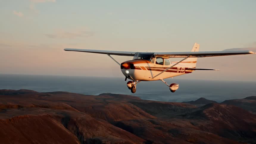 Singleengine airplane flying over mountains at sunset