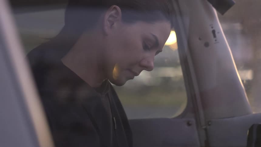 Woman seated inside an aircraft looks down near the window