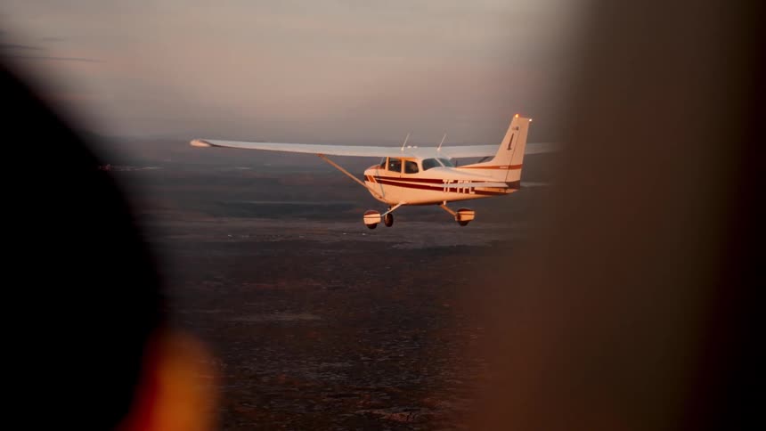 Aircraft parallels a second plane while flying over foggy terrain on an overcast day