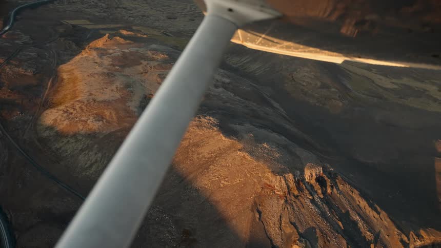 An airplane flying over a coastal terrain at sunset