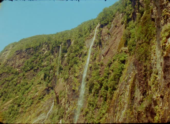 Waterfall flowing down a rocky cliff covered with vegetation