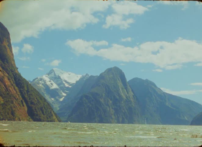 Wide shot of a scenic fiord with majestic mountains and a rocky shoreline