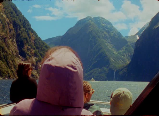 Travelers on a boat enjoying the natural scenery of the sea surrounded by imposing mountains