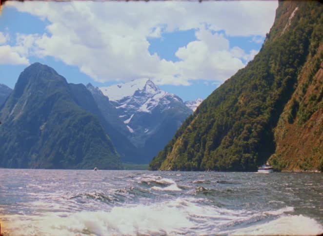 Waves crash against the green mountains