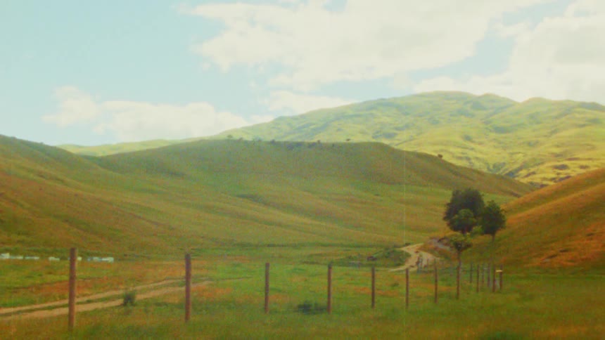 A large expanse of grassland surrounded by hills in the countryside