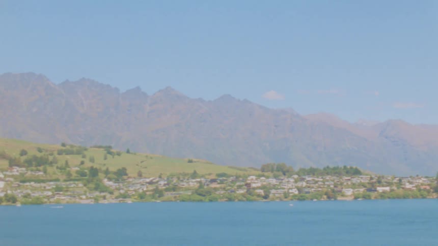 Wide panoramic shot of a lakeside town nestled against distant mountains