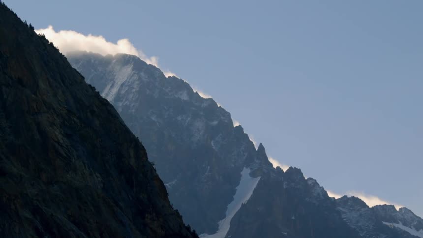 Clouds lift off the top of a snowy mountain
