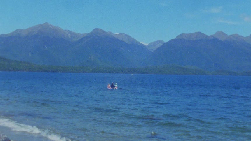 Boat with people on lake surrounded by forested mountains