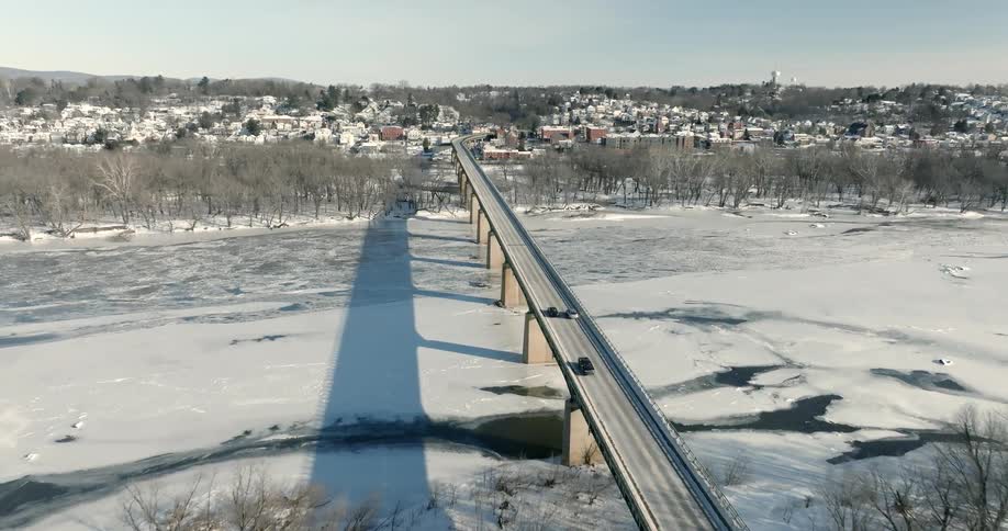 Cars driving on a long bridge over a frozen river during winter