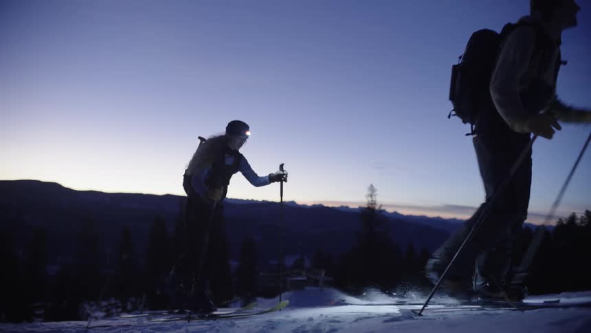 Two people cross country skiing at dusk