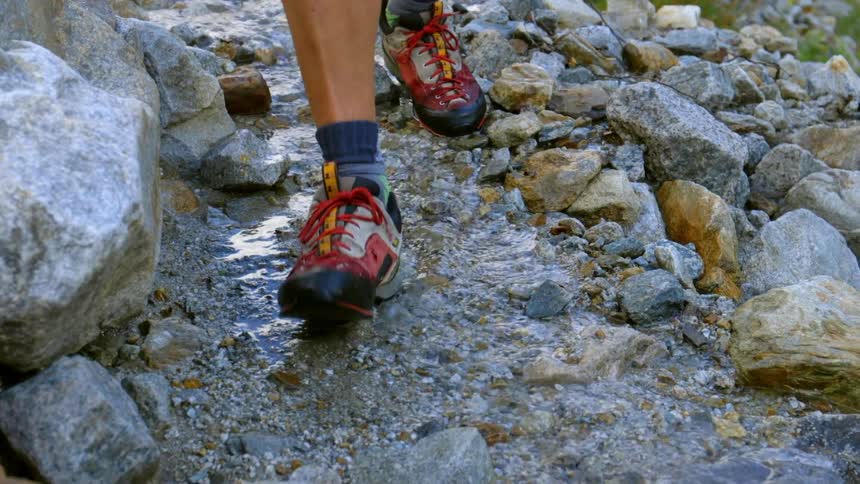 Person wearing hiking shoes walks through a rocky stream