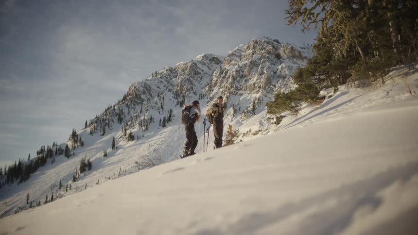 Two skiers standing on a snow covered mountain slope high five each other