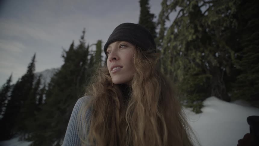 Person with black beanie and backpack in snowy forest