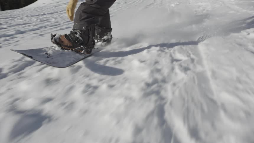 Snowboarder keeps his balance sliding down a snow covered mountain slope