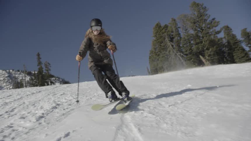 Skier holds their poles as they slide down a snow covered mountain slope