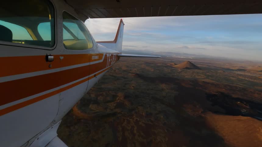Small airplane flying over a rural mountain area