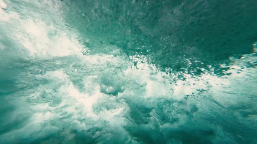 Under the ocean surface a wave can be seen crashing down