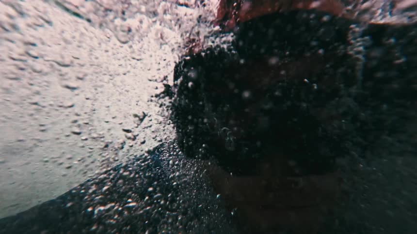 Bubbles surround part of a submerged body in clear water