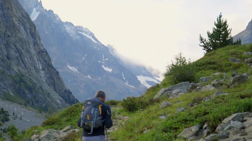 A man wearing a backpack hikes a rocky trail