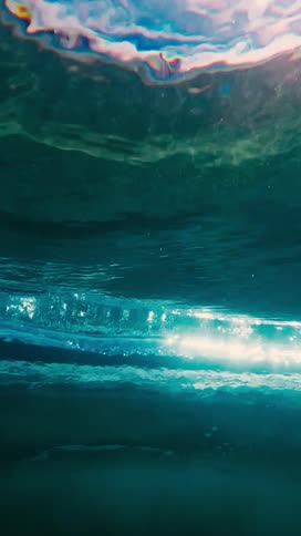 Water surface seen from below with light reflecting in a blue tone