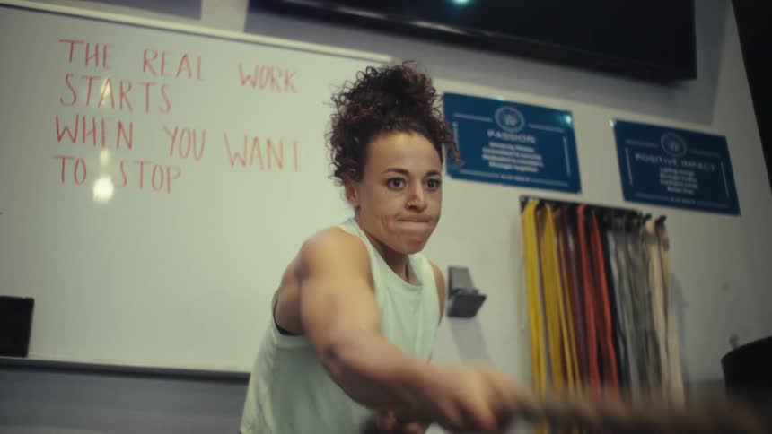 Woman pulls a rope during functional training in a gym
