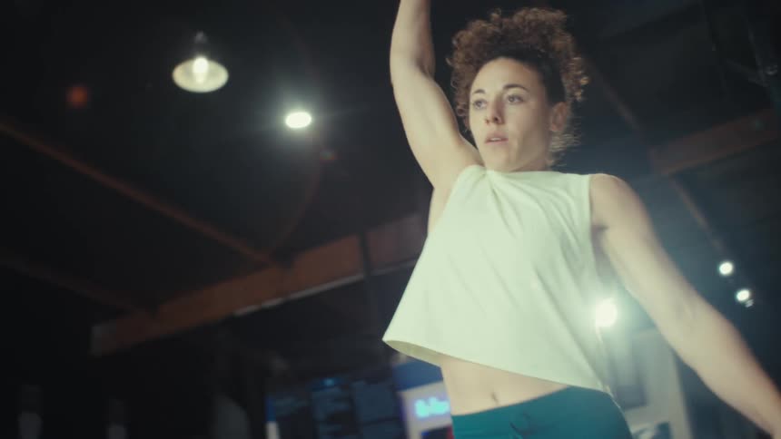 An athletic woman lifts heavy dumbbells during an intense gym workout