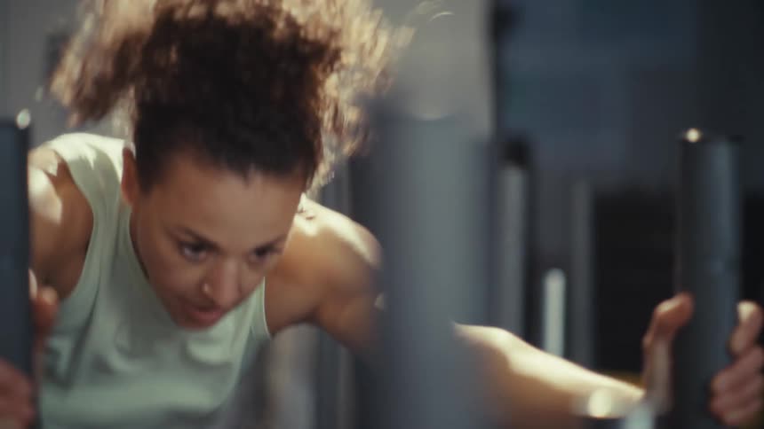 Woman exercises holding equipment bars in a gym