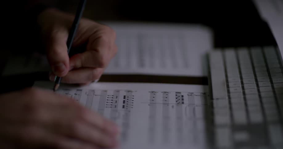 Person writes on sheet music