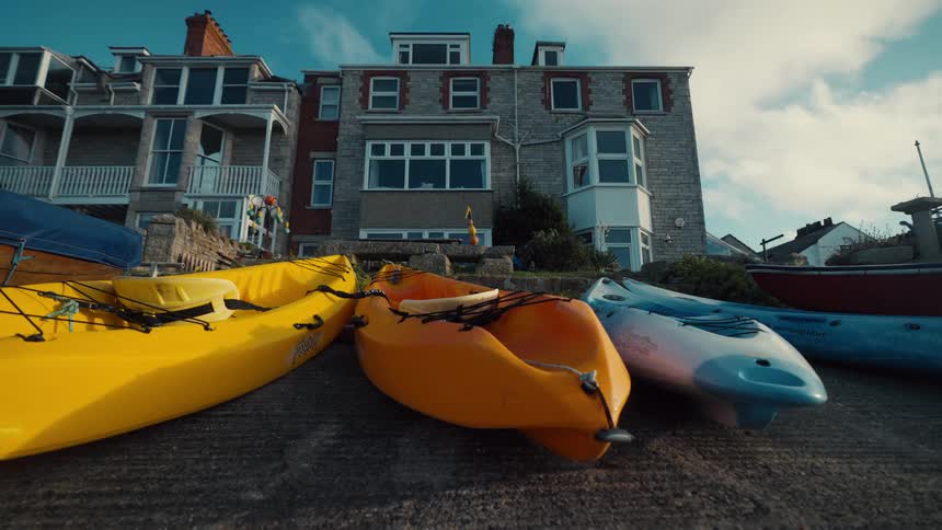 Yellow orange and blue kayaks lined up on a ramp in front of residential houses