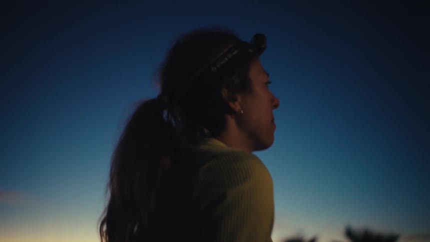 Runner wearing a headlamp leans forward at dawn under a clear sky