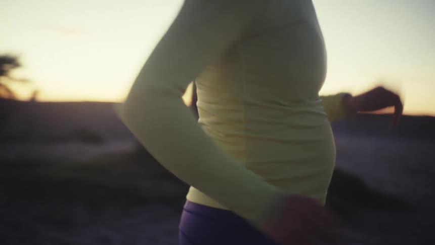 Woman wearing a headlamp as she jogs at dusk in a desert neighborhood