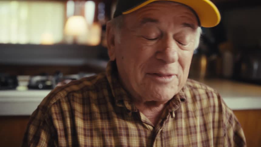Elderly man smiling with veteran cap in home kitchen