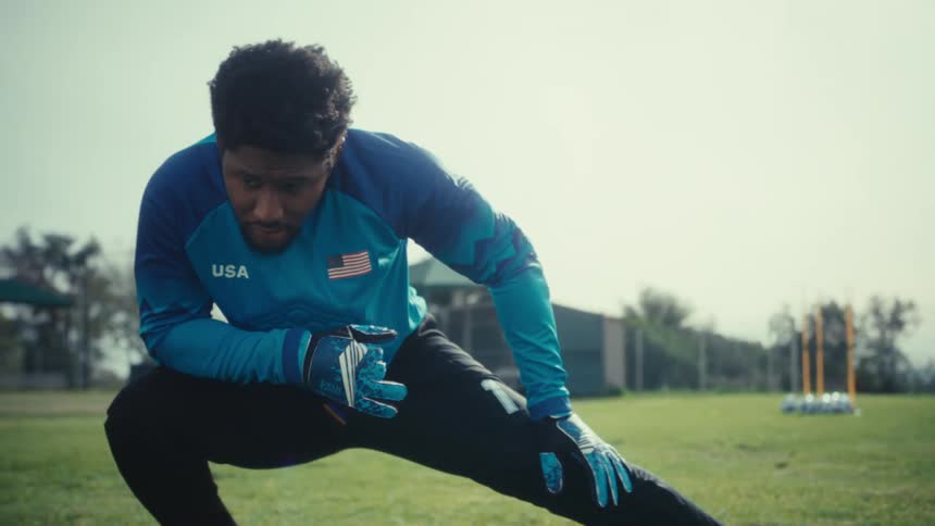 Goalkeeper stretching on a grassy field