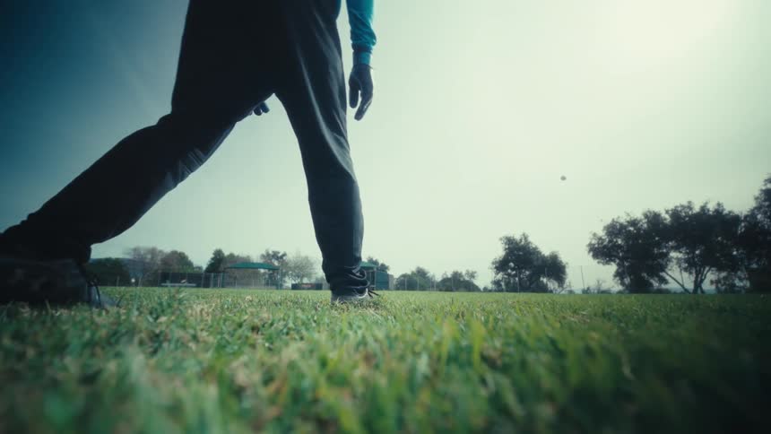 Soccer ball sits on the grass in a field as a player kicks it away