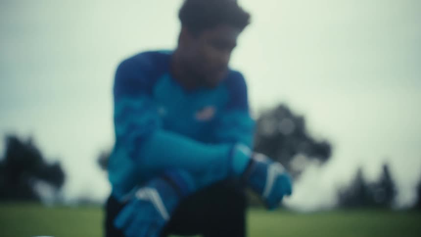 Soccer player kneels on the field near soccer balls