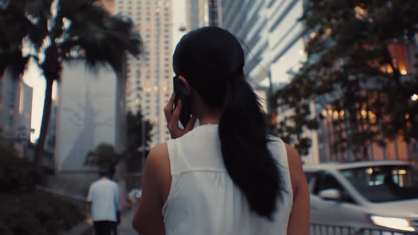 Young woman walking downtown talking on her smart phone