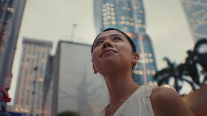 The woman is looking up at the tall buildings