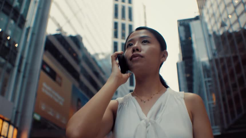 Young woman walking downtown talking on her smart phone