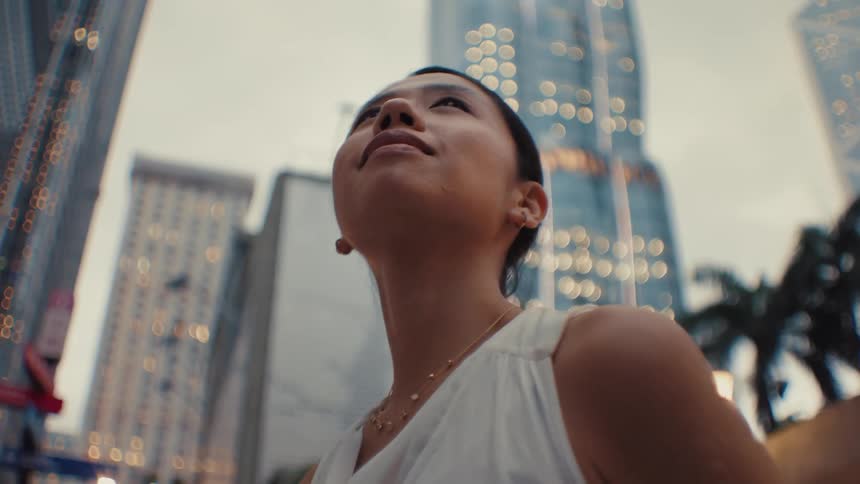 The woman smiles while looking around the city