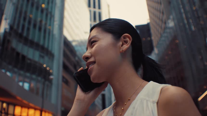 Young woman standing downtown when she answers her phone and cheers in celebration