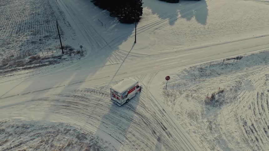 Aerial view of a uhaul truck turning at a snowcovered intersection