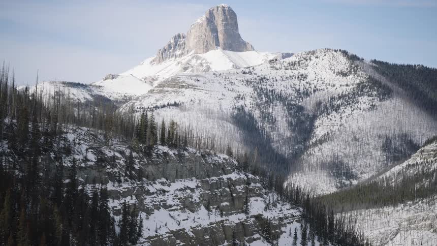 Rocky mountain covered in snow with forested slopes and surrounding valleys