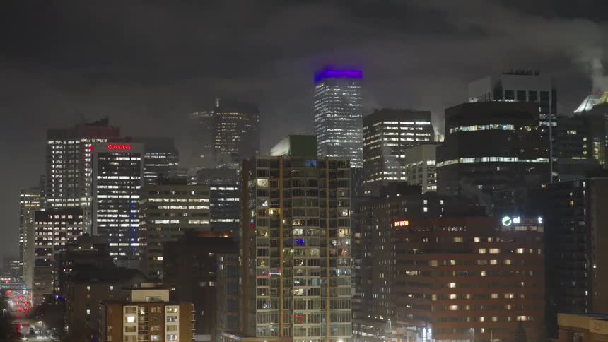 Metropolitan towers and skyscrapers with lights glowing on the city skyline under a cloudy sky