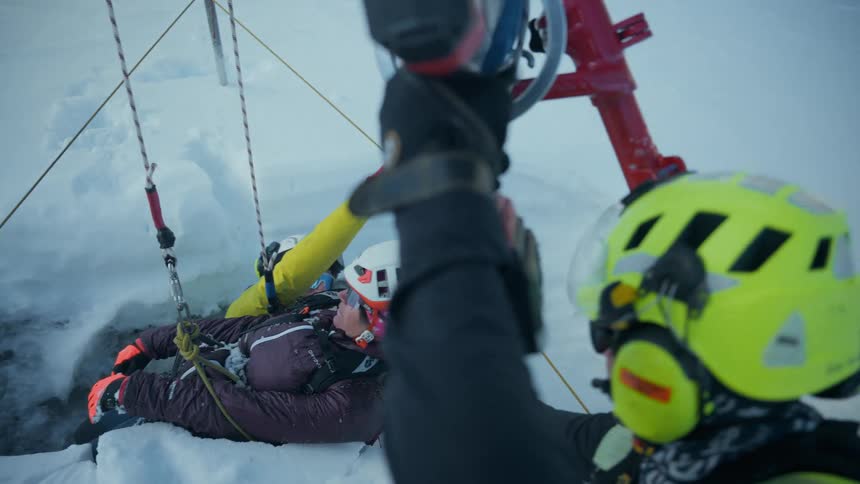 Mountain rescue helps a person using a pulley system on a snowy winter day