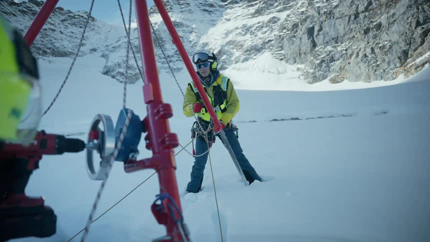 Scientist uses specialized drilling equipment on a snowy mountain glacier for research