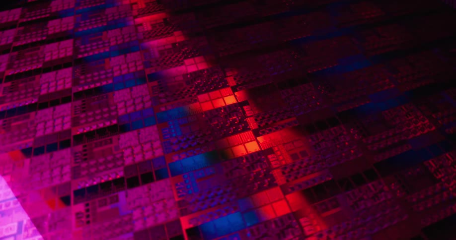 A vast array of semiconductor chips on a wafer illuminated by vibrant shifting lights in shades of pink red and blueas the camera pans across the surface the colorful reflections highlight the intricate repetitive patterns of the integrated circui